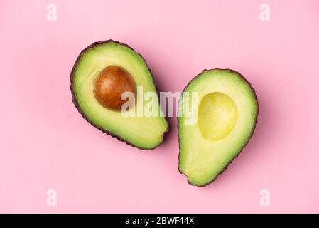 Avocado Hälften mit Kern auf rosa Hintergrund. Minimalistischer Stillleben Hintergrund Stockfoto