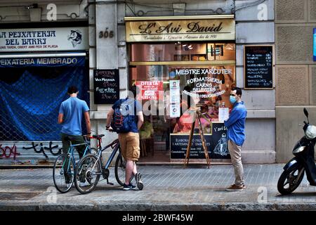 Drei junge Männer warten auf einen Feinkostladen in Barcelona, Spanien. Stockfoto