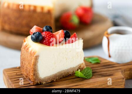 Käsekuchen-Scheibe mit Sommerbeeren auf der Oberseite. Ein Stück New yorker Käsekuchen mit Beeren Stockfoto