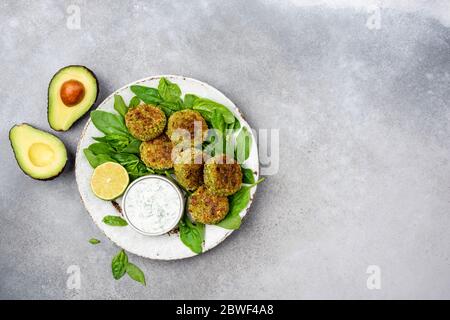 Vegetarische Falafel-Patties Mit Joghurtsauce. Gesunde Gemüse Avocado Spinat Chickpea Fritters. Ansicht von oben kopieren Raum auf grauen Beton Hintergrund Stockfoto