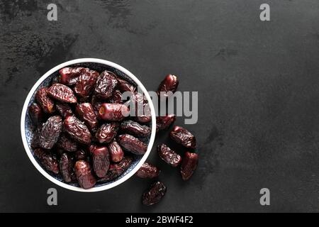 Getrocknete Datteln in Schale auf schwarzem Hintergrund mit Kopierraum für Text, Draufsicht. Schwarze Beton Hintergrund Textur Stockfoto