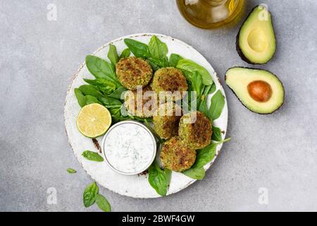 Falafel mit Joghurtsauce. Vegetarische Spinat Avocado Kichererbsen fritters Falafel mit Joghurt-Sauce auf dem Teller serviert. Draufsicht. Gesundes vegetarisches Essen Stockfoto