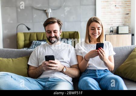 Junges Paar mit Smartphones zu Hause. Stockfoto