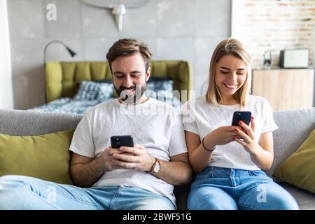 Junges Paar mit Smartphones im Wohnzimmer Stockfoto