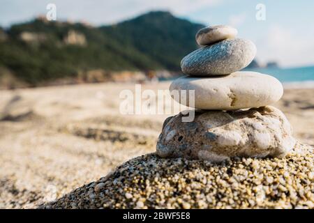 Steinpyramide auf Kiesstrand symbolisieren Stabilität, Zen, Harmonie, Gleichgewicht mit Berg und Himmel im Hintergrund. Stockfoto