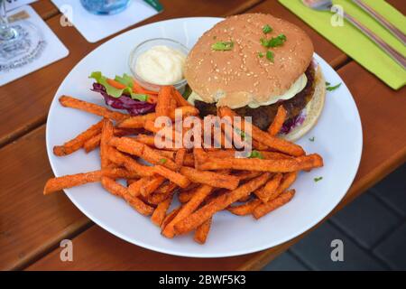 Gesunde vegetarische Burger mit Süßkartoffelfries serviert mit etwas Salat auf einem Teller. Stockfoto