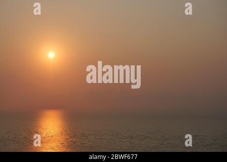 Luftaufnahme des Meeres bei Sonnenaufgang, die Sonne auf der Wasseroberfläche reflektiert, begann Horizon orange mit Goldfarbe in tropischen Gebieten, Thailand zu drehen Stockfoto