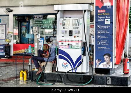 Kochi, Indien - Mai 2020: Ein Tankstellenarbeiter schaut am 31. Mai 2020 in Kochi, Kerala, Indien, auf sein Handy, während er eine Maske trägt. Stockfoto