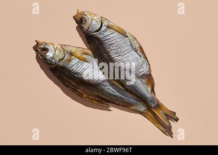 Zwei getrocknete oder ruckige salzige Taranka, lecker Clipfish auf rosa Hintergrund. Beliebte Biervorspeise. Traditionelle Art der Fischkonservierung. Nahaufnahme Stockfoto