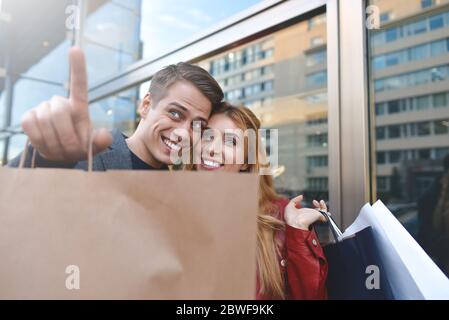 Schönes Paar mit Einkaufstaschen ist reden und lächeln beim Einkaufen in der Mall konzentrieren sich auf die Frau. Heiße Rabatte Stockfoto