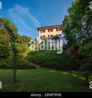 Schönes Haus mitten im Grünen mit einer modernen Stahlbetonverbindung und einem großen Fenster. Stockfoto