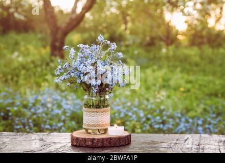 Bouquet von wilden Blumen Myosotis auch bekannt als Vergiss mich nicht s oder Skorpion Gräser in Spitze Burlap Tuch dekoriert Baby-Food-Glas. Preiswerter Jahrgang p Stockfoto