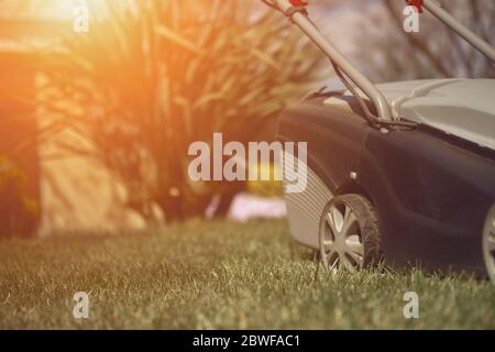 Schwarz und grau moderner Grasschneider, der grünen Rasen in einem Garten des Landhauses mäht. Gartengeräte. Nahaufnahme Stockfoto