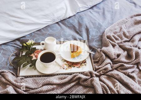 Frühstück im Bett Scheibe Cheesesescake mit einer Tasse Kaffee und Blumen in einem Tablett Stockfoto