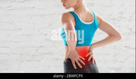 Ansicht der jungen Frau, die nach dem Training im Fitnessstudio Schmerzen im unteren Rücken fühlt, kopieren Sie den Bereich Stockfoto