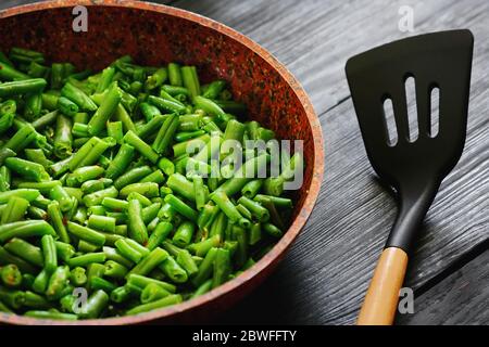 Vegetarisches Essen. Gebratene Bohnen in einer Pfanne. Stilvoller Hintergrund für Design. Minimalismus. Gesunde Lebensmittel aus Gemüse. Stockfoto