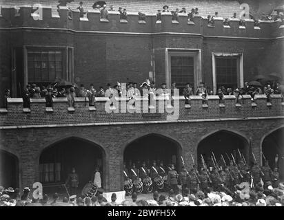 Friedensproklamation die am Dienstag vom König unterzeichnete "Friedensproklamation" wurde am Mittwoch an fünf Punkten in London öffentlich vorgelesen. Die Lesung wurde mit all seinen malerischen und interessanten Zeremonie von Offizieren des College of Arms in ihren wunderschönen Tabards durchgeführt. Sie wurden von imposanten Prozessionen begleitet. Die Szene im St James Palace London 1919 Stockfoto