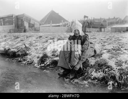 Eine holländische Idylle EIN charmantes Foto eines fröhlichen kleinen holländischen Mädchens, das sich auf einen Skate in Nordholland vorbereitet 10. Dezember 1921 Stockfoto