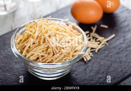 Schüssel mit traditionellen türkischen Nudeln (roh) mit Eiern auf dem Tisch. Stockfoto