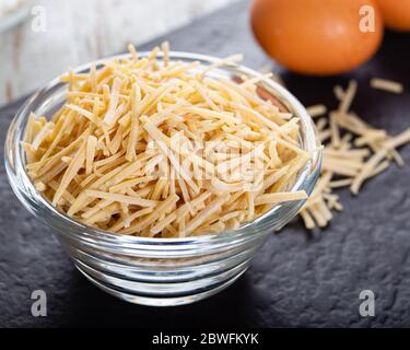 Schüssel mit traditionellen türkischen Nudeln (roh) mit Eiern auf dem Tisch. Stockfoto