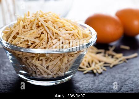Schüssel mit traditionellen türkischen Nudeln (roh) mit Eiern auf dem Tisch. Stockfoto