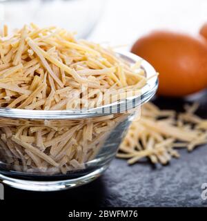 Schüssel mit traditionellen türkischen Nudeln (roh) mit Eiern auf dem Tisch. Stockfoto