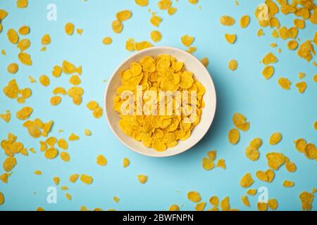 Müsli (Cornflakes) zum Frühstück in einer rosa Schüssel auf blauem Hintergrund. Minamal Art Creative Food Konzept Stockfoto