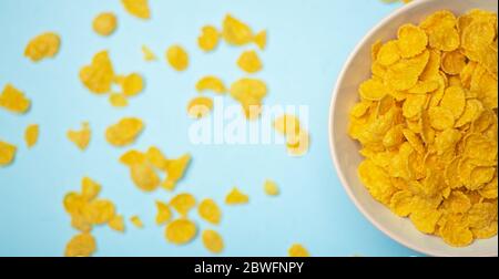 Müsli (Cornflakes) zum Frühstück in einer rosa Schüssel auf blauem Hintergrund. Minamal Art Creative Food Konzept Stockfoto