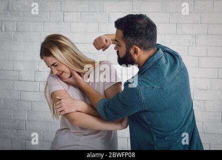Aggression zu Hause. Ehemann schlägt Frau, Frau wendet sich ab Stockfoto