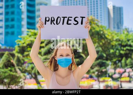 Frau in medizinischer Maske verhindert Coronavirus-Krankheit hält ein PLAKAT PROTEST handgeschriebenen Text - Schriftzug isoliert auf weiß. Coronovirus COVID 19 Stockfoto
