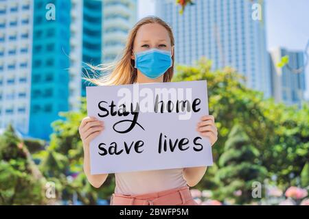 Frau in medizinischer Maske verhindert Coronavirus-Krankheit hält ein Poster Stay Home Save Lives handgeschriebener Text - Schriftzug isoliert auf weiß. Coronovirus Stockfoto