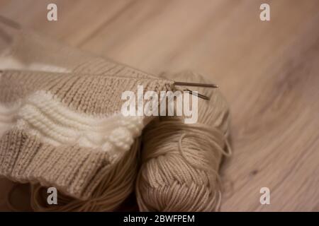 Braun stricken auf hellem Hintergrund.Stricknadeln und Skeins aus Wolle, Handstricken. Selektiver Fokus. Stockfoto