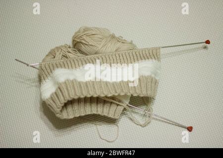 Braun stricken auf hellem Hintergrund.Stricknadeln und Skeins aus Wolle, Handstricken. Selektiver Fokus. Stockfoto