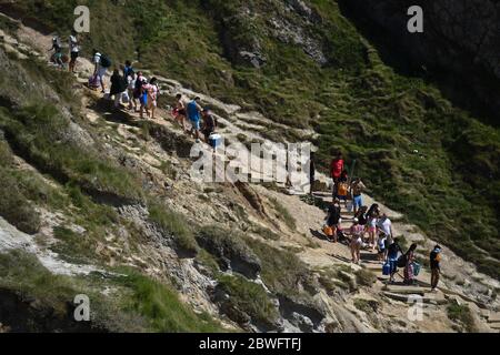 Die Menschen machen sich auf den Weg zum Strand von Durdle Door, nahe Lulworth, in Dorset, nachdem die Öffentlichkeit daran erinnert wurde, soziale Distanzierung nach der Lockerung der Beschränkungen der Lockerung des Coronavirus in England zu praktizieren. Stockfoto