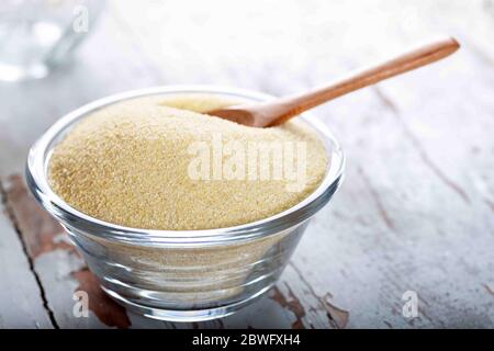 Grieß in Glasschüssel mit Löffel auf Holzhintergrund. Stockfoto