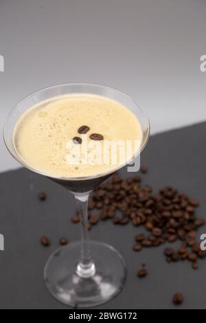 Ein Espresso Martini in einem martiniglas serviert und mit gerösteten Kaffeebohnen garniert. Das Glas wird mit frisch gerösteten Kaffeebohnen gesehen. Stockfoto