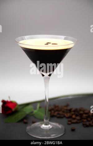 Ein Espresso Martini in einem martiniglas serviert und mit gerösteten Kaffeebohnen garniert. Das Glas wird mit frisch gerösteten Kaffeebohnen gesehen. Stockfoto