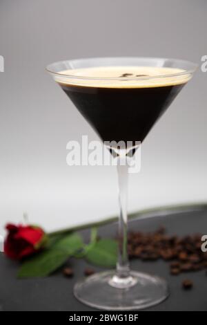 Ein Espresso Martini in einem martiniglas serviert und mit gerösteten Kaffeebohnen garniert. Das Glas wird mit frisch gerösteten Kaffeebohnen gesehen. Stockfoto