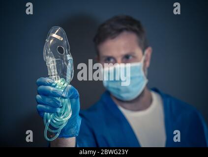 COVID-19 Ausbruch. Erschöpfter Arzt mit nichtinvasivem Beatmungsgerät. Medizinische Behandlung und Mangel an Ausrüstung für Coronavirus-infizierte Patienten mit S Stockfoto