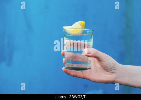 FEMA Hand hält Glas Wasser mit Zitrone Stockfoto
