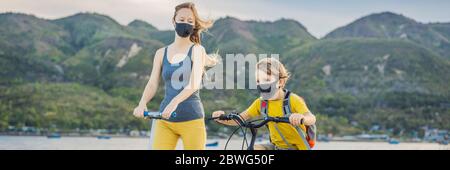 Aktive Schulkind Junge und seine Mutter in medizinischen Maske Reiten ein Fahrrad mit Rucksack an sonnigen Tag. Fröhliches Kinderradeln auf dem Weg zur Schule. Gehen Sie zu Stockfoto