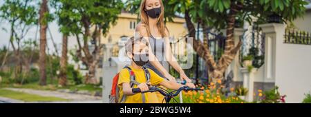 Aktive Schulkind Junge und seine Mutter in medizinischen Maske Reiten ein Fahrrad mit Rucksack an sonnigen Tag. Fröhliches Kinderradeln auf dem Weg zur Schule. Gehen Sie zu Stockfoto