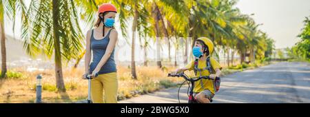 Aktive Schulkind und seine Mutter in medizinischen Maske und Schutzhelm Reiten ein Fahrrad mit Rucksack an sonnigen Tag. Fröhliches Kinderradeln auf dem Weg zur Schule. Sie Stockfoto