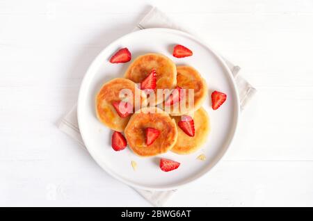 Hausgemachte Pfannkuchen mit Hüttenkäse und Erdbeerscheiben, Syrniki. Draufsicht, flaches Lay Stockfoto