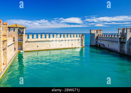 Sirmione, Italien, 11. September 2019: Kleiner befestigter Hafen mit türkisfarbenem Wasser, Scaligero Burg Castello Festung, Stadt am Gardasee, mittelalterliche Burg mit Steintürmen und Backsteinmauern, Lombardei Stockfoto