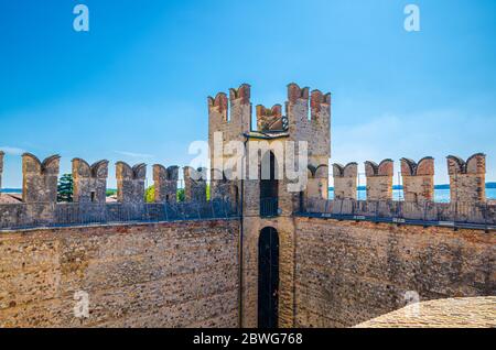 Sirmione, Italien, 11. September 2019: Turm und Steinmauer mit Schwalbenschwanz-Meerlonen von Scaligero Castle Castello mittelalterliche Festung, Sirmione Stadt am Gardasee, blauer Himmel Hintergrund, Lombardei Stockfoto