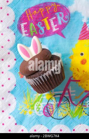 M&S Easter Cupcake auf Serviette Serviette Serviette - Mini-Schokolade Cupcakes mit Schokolade Buttercreme und Ostern Dekorationen - Osterhasen Ohren Stockfoto