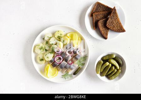 In Scheiben geschnittener Heringsfisch mit gekochten Kartoffeln. Eingelegte Gurken. Russische Küche. Draufsicht, flaches Lay Stockfoto