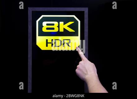 Moskau, Russland - 04. Oktober 2019: Weiblicher Finger zeigt auf 8k hdr-Qualitätsymbol. Hintergrund ist schwarz Stockfoto