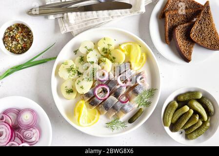 In Scheiben geschnittener Heringsfisch mit gekochten Kartoffeln. Eingelegte Gurken. Russische Küche. Draufsicht, flaches Lay Stockfoto